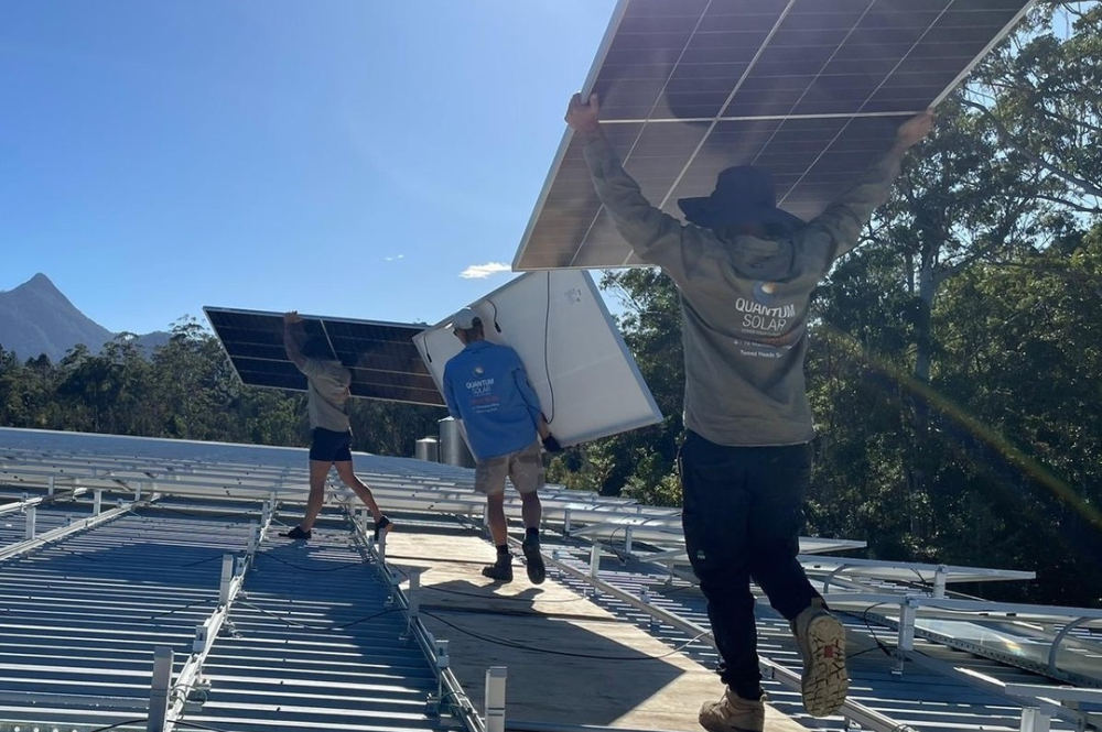 Image of the Quantum Solar team installing solar panels on a commercial roof.